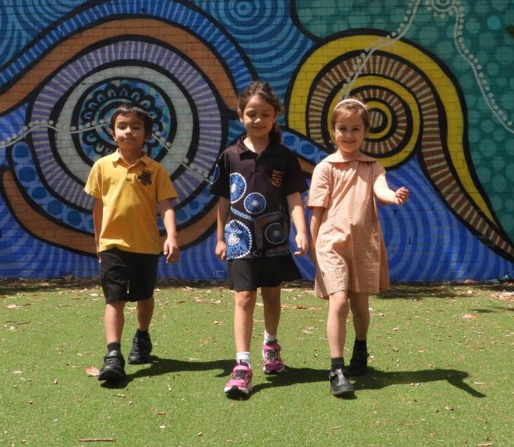 three students walking in front of a mural